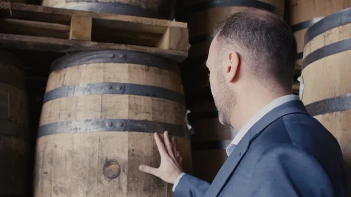 A man inspecting a bourbon barrel on the rick