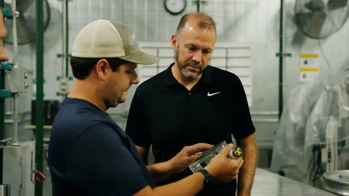 Two distillery workers examining a bourbon sample